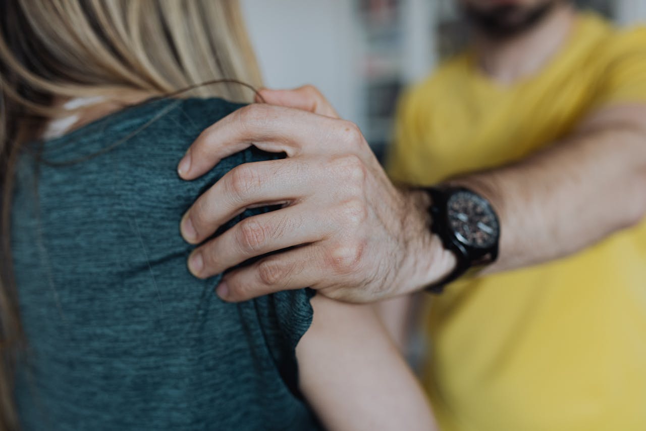 Man forcibly grabbing a woman by the arm in the workplace.