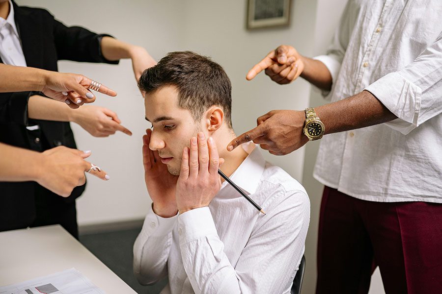 A male worker being pointed at by his co-workers